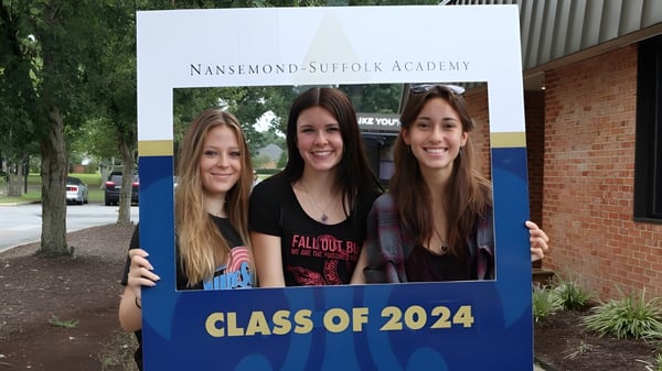 Drei Schülerinnen posieren vor einem Schild der Nansemond-Suffolk Academy mit der Aufschrift Klasse 2024.
