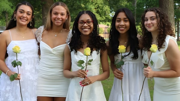Fünf Schülerinnen der Nansemond-Suffolk Academy stehen mit gelben Rosen in einem grünen Außenbereich.