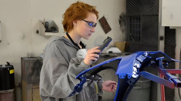 Eine Person arbeitet an einem blauen Motorrad in der Werkstatt der Napanee District Secondary School.