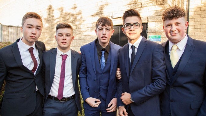 Eine Gruppe von fünf Jungen in formeller Kleidung steht vor einem Backsteingebäude der Napier Boys High School.