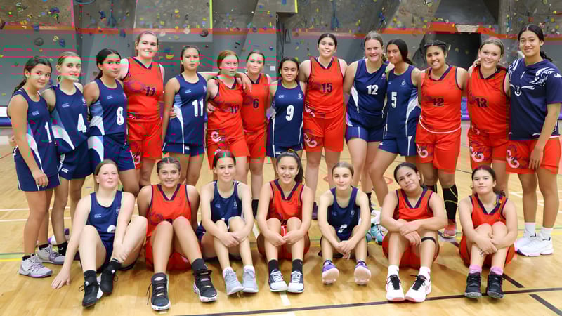 Eine Gruppe junger Basketballspielerinnen der Napier Girls' High School posiert gemeinsam auf dem Basketballfeld.
