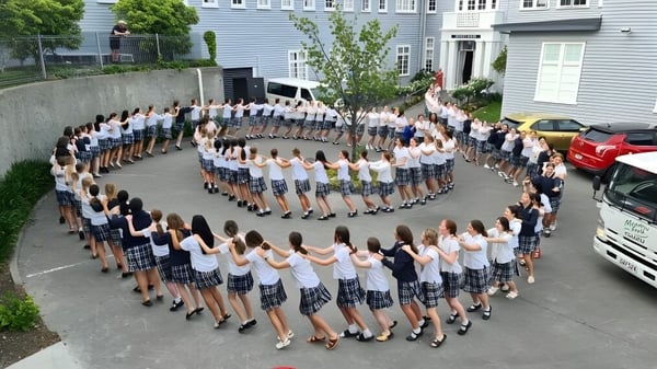 Eine Gruppe Schülerinnen der Napier Girls' High School steht im Freien in einer kreisförmigen Formation vor dem Schulgebäude.