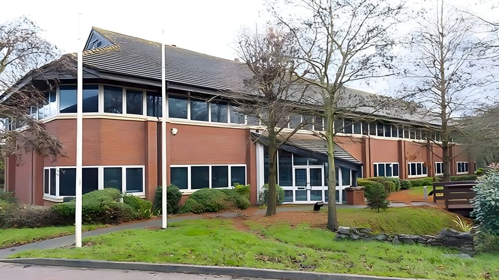 Das mehrstöckige Backsteingebäude des National Mathematics & Science College steht umgeben von Bäumen und gepflegtem Rasen.