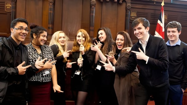 Eine Gruppe von Schülern steht im National Mathematics and Science College vor historischen Holzverkleidungen.