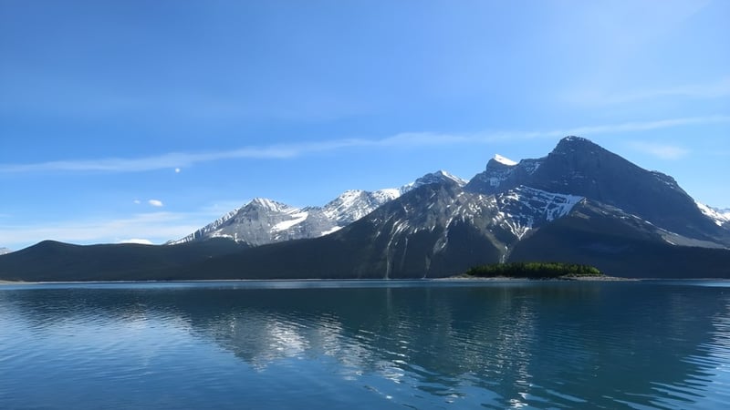 Berglandschaft mit schneebedeckten Gipfeln und einem spiegelglatten See im Vordergrund nahe der National Sport School.