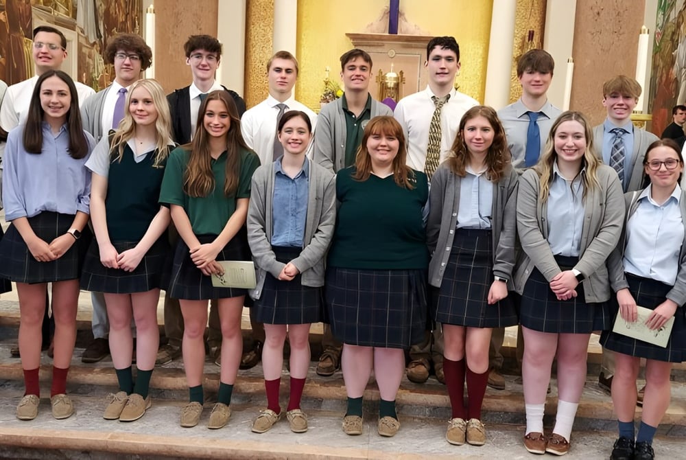 Eine Gruppe Schülerinnen und Schüler steht zusammen im Flur der Nativity BVM High School mit verzierter Architektur im Hintergrund.