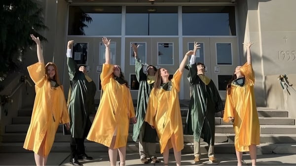 Schüler der Nativity BVM High School stehen in bunten Gewändern auf der Treppe und heben synchron die Arme.
