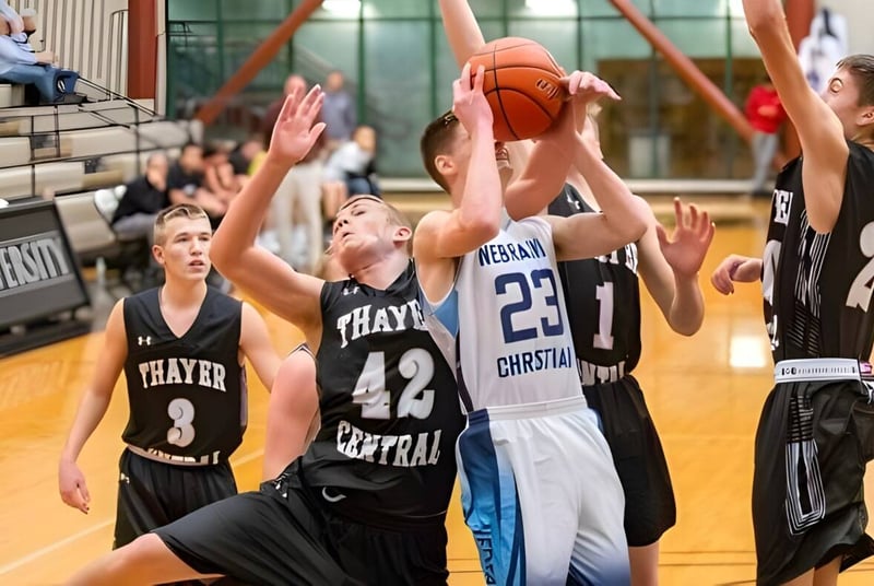 Schüler der Nebraska Christian Schools spielen Basketball auf dem Spielfeld mit Zuschauern im Hintergrund.