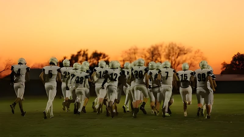 Futuristische humanoide Figuren marschieren über ein Grasfeld bei Sonnenuntergang auf dem Gelände der Nebraska Christian Schools.