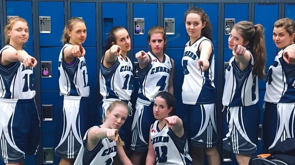 Eine Gruppe junger Athletinnen der Nechako Valley Secondary School posiert gemeinsam im Spindraum in Sportbekleidung.