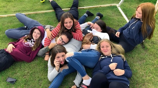 Eine Gruppe Schülerinnen der Nechako Valley Secondary School liegt auf dem Gras und umarmt sich im Freien.