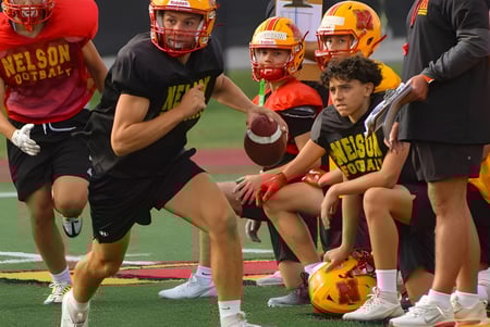 Eine Gruppe junger Fußballspieler der Nelson High School steht mit Trikots und Schutzkleidung auf dem Sportfeld.