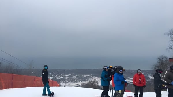 Eine Gruppe von Schülern der Nelson High School steht auf einem verschneiten Hang vor nebliger Berglandschaft.