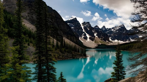 Ein ruhiger türkisfarbener See umgeben von schneebedeckten Bergen und immergrünen Wäldern nahe der Nepean High School.
