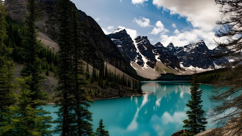 Ein ruhiger türkisfarbener See umgeben von schneebedeckten Bergen und immergrünen Wäldern nahe der Nepean High School.