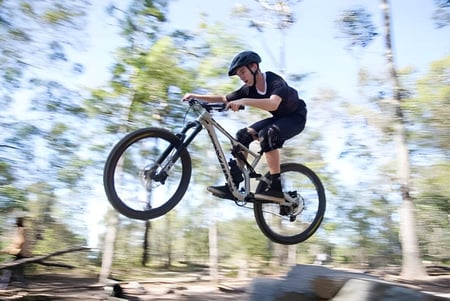 Eine Person fährt auf einem Fahrrad durch einen bewaldeten Bereich auf dem Gelände der Nerang State High School.