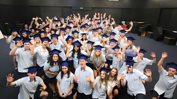 Eine Gruppe von Schülerinnen und Schülern der Nerang State High School hebt auf dem Schulgelände die Hände zur gemeinsamen Feier.