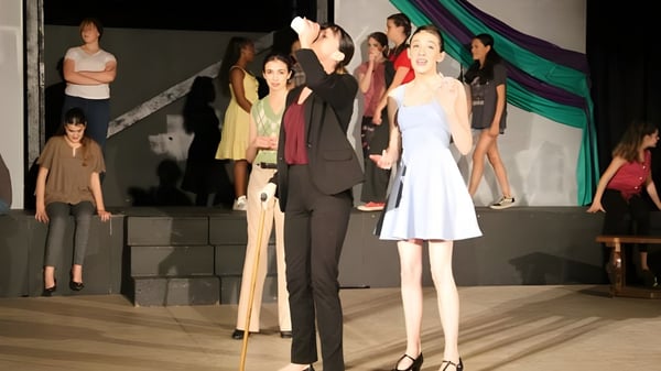 Eine Gruppe von Schülerinnen und Schülern der New Garden Friends School steht in formeller Kleidung auf einer Bühne vor einem Vorhang.