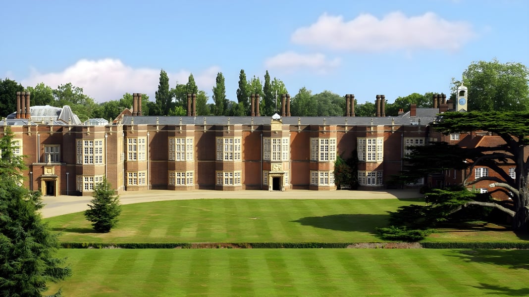Das prächtige Backsteingebäude der New Hall School mit großen Rundbogenfenstern und gepflegtem Rasen im Vordergrund.