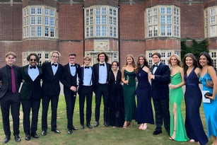 Eine Gruppe von Personen posiert vor dem historischen Backsteingebäude der New Hall School.