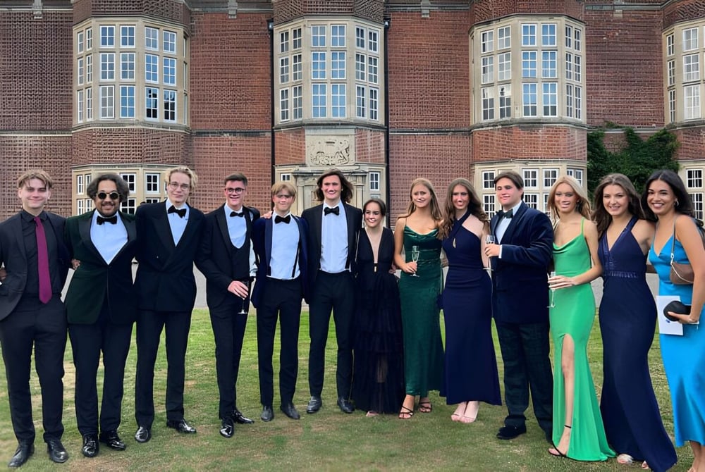 Eine Gruppe von Personen posiert vor dem historischen Backsteingebäude der New Hall School.