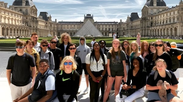 Eine Gruppe Schülerinnen der New Hall School posiert vor dem Louvre Museum in Paris mit der gläsernen Pyramide im Hintergrund.