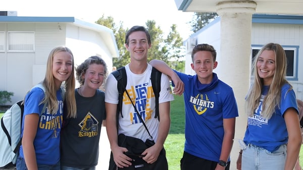 Eine Gruppe von fünf Schülerinnen und Schülern steht gemeinsam vor einem Gebäude auf dem Campus der New Hope Christian School.