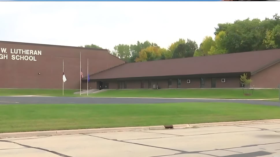 Das große braune Gebäude der N.E.W. Lutheran High School ist von einer Grasfläche und Bäumen umgeben.