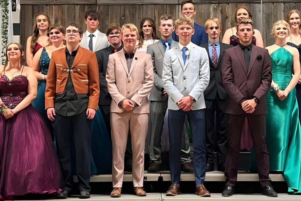 Eine Gruppe formell gekleideter Schülerinnen und Schüler steht vor einem hölzernen Gebäude auf dem Gelände der New Norway School.