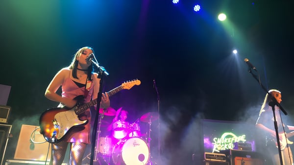 Schülerin der New Plymouth Girls’ High School spielt E-Gitarre auf der Bühne mit Band und Drumset im Hintergrund.