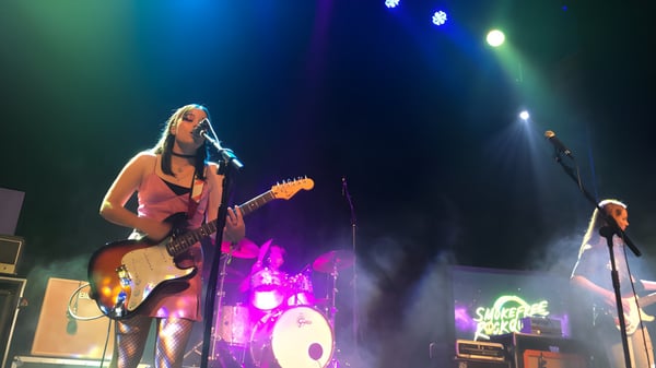 Eine Schülerin der New Plymouth Girls’ High School spielt auf der Bühne eine E-Gitarre mit Schlagzeug und Verstärkern im Hintergrund.