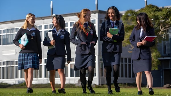 Fünf Schülerinnen der New Plymouth Girls’ High School stehen gemeinsam auf dem Schulcampus vor einem Gebäude.