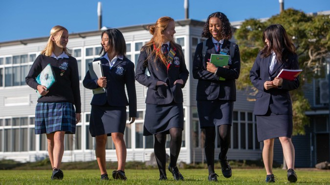 Eine Gruppe Schüler der New Plymouth Girls’ High School steht gemeinsam auf dem Schulgelände vor einem Gebäude.