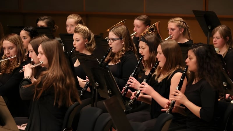 Eine Gruppe junger Musiker der New Sarepta Community High School spielt verschiedene Instrumente wie Flöten und Geigen auf der Bühne.