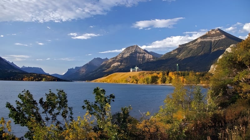 Ein alpiner See mit schneebedeckten Bergen und herbstlichem Laub in der Nähe der New Sarepta Community High School.