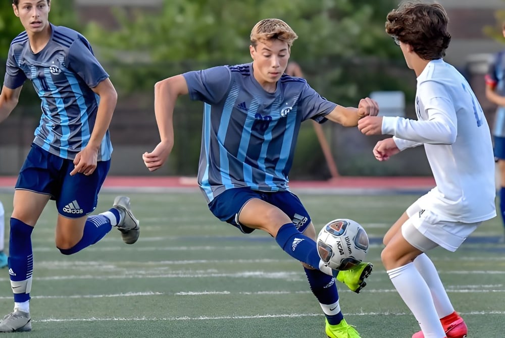 Schüler der New Westminster Secondary School spielen ein Fußballspiel auf einem grünen Spielfeld.