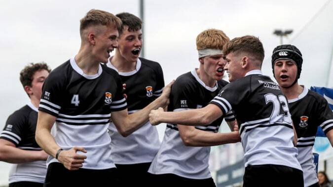 Eine Gruppe Schüler in Sportuniformen des Newbridge College feiert gemeinsam auf dem Spielfeld.