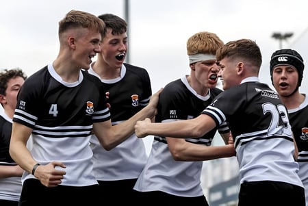 Eine Gruppe Schüler im Sportdress feiert gemeinsam auf dem Spielfeld des Newbridge College.
