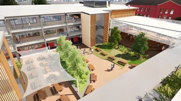 Das moderne mehrstöckige Gebäude mit Glaswänden und Holzelementen auf dem Campus der Newcastle High School ist von Grünflächen und einem gepflasterten Hof umgeben.