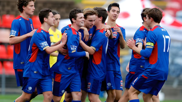 Schüler der Newcastle High School stehen im blauen Trikot gemeinsam auf dem Fußballfeld.