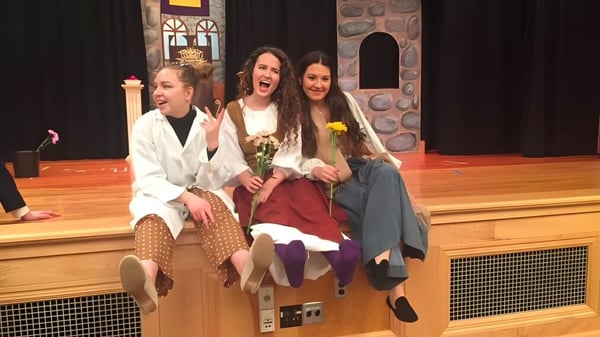 Drei Schülerinnen in farbenfrohen Kostümen stehen auf der Bühne im Newcomb Central School District.