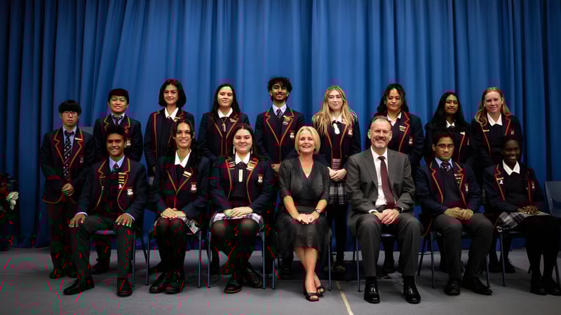 Eine Gruppe Schüler in formeller Kleidung sitzt vor einem blauen Vorhang auf dem Campus des Newlands College.
