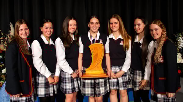 Schülerinnen des Newlands College stehen zusammen und halten eine Trophäe.