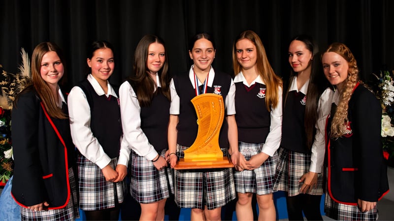 Schülerinnen des Newlands College stehen zusammen und halten eine Trophäe.
