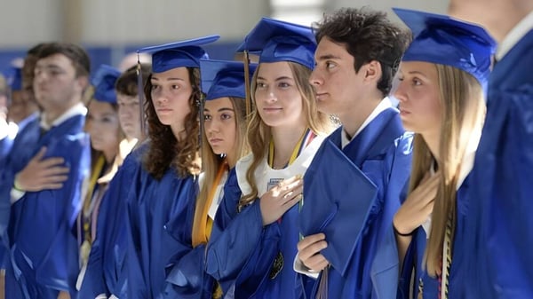 Eine Gruppe von Absolventinnen und Absolventen in blauen Talaren steht auf dem Abschlussfoto der Newman Central Catholic High School.
