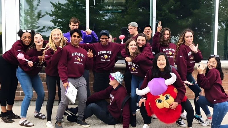 Eine Gruppe von Schülerinnen und Schülern der Newmarket High School steht vor einem Gebäude mit großen Fenstern und Bäumen.