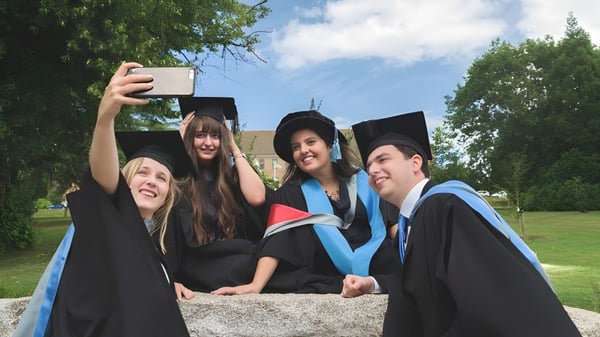 Vier Absolventen des Newstead College in akademischen Talar nehmen im Freien ein Selfie auf.