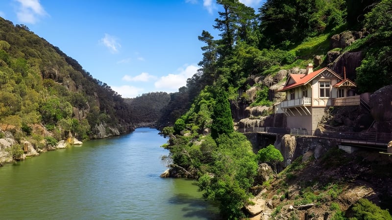 Eine malerische Flusslandschaft mit Holzhaus und Bergen auf dem Gelände von Newstead College.