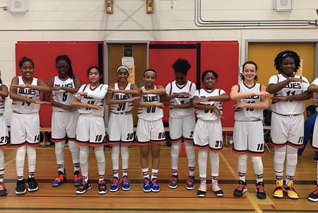 Eine Gruppe junger Basketballspielerinnen steht im Gymnasium der Newtonbrook Secondary School zusammen.