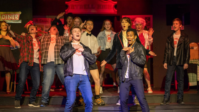 Eine Gruppe Schüler steht auf der Bühne der Newtown School vor einem Diner-Schild.